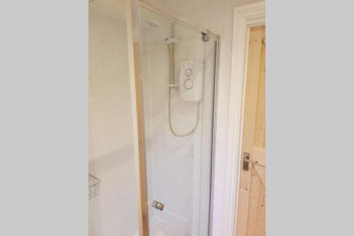 a shower with a glass door in a bathroom at Cosy, self contained annex in Cambridge