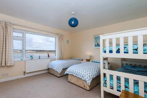 a bedroom with two bunk beds and a window at AEL-Y-BRYN-5 BED- DRAMATIC SEA VIEWS - Sleeps 12 in Trearddur