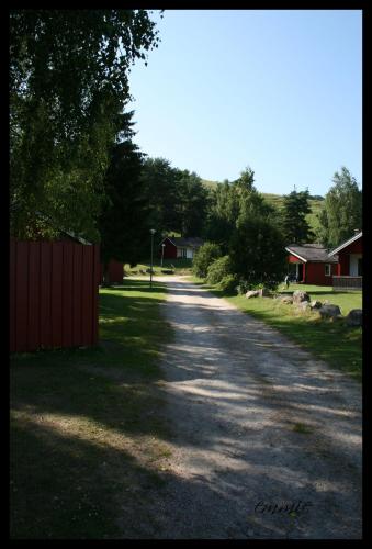 a dirt road with a fence and a house at Degeberga Stugby in Degeberga
