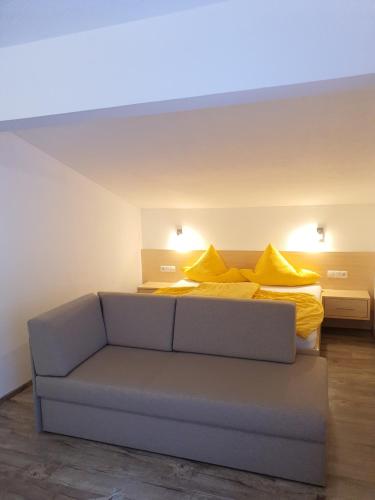 Habitación con sofá y cama con almohadas amarillas. en Apart Felsenhof, en Längenfeld