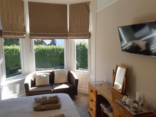 Cette chambre comprend un lit, un canapé et une télévision. dans l'établissement Ferndale Lodge, à Ambleside