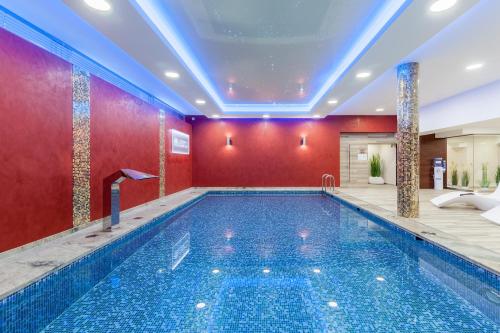 uma piscina num quarto de hotel com uma parede vermelha em Hotel Beskid em Nowy Sącz