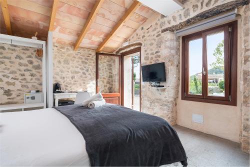 a bedroom with a bed and a tv and windows at Hotel Turixant in Mancor del Valle