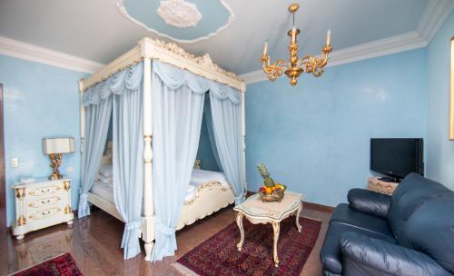 a bedroom with a canopy bed and a couch at Seehotel Porcia in Pörtschach am Wörthersee