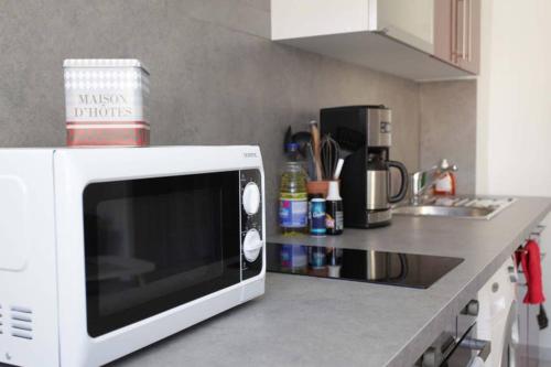 Un four micro-ondes blanc est installé au-dessus d'un comptoir de cuisine. dans l'établissement Studio à Nice ensoleillé proche centre et plage, à Nice