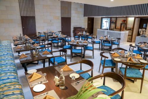a restaurant with wooden tables and blue chairs at Royal Orchid Golden Suites Pune in Pune