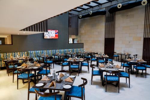 un comedor con mesas y sillas azules en Royal Orchid Golden Suites Pune en Pune