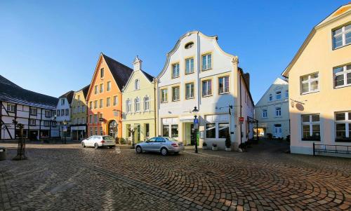 a cobblestone street in a town with buildings at Hotel Johann in Warendorf