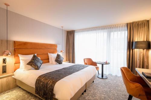 a hotel room with a bed and a desk at Hotel Restaurant Van Der Valk Nivelles-Sud in Nivelles