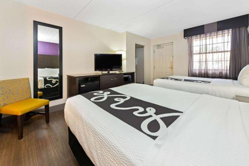 a hotel room with two beds and a tv at La Quinta Inn by Wyndham Miami Airport North in Miami