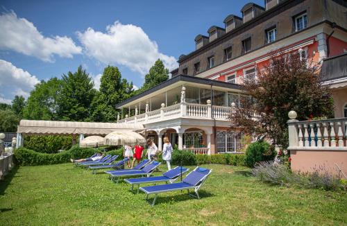 a row of blue lounge chairs in front of a building at Seehotel Porcia in Pörtschach am Wörthersee