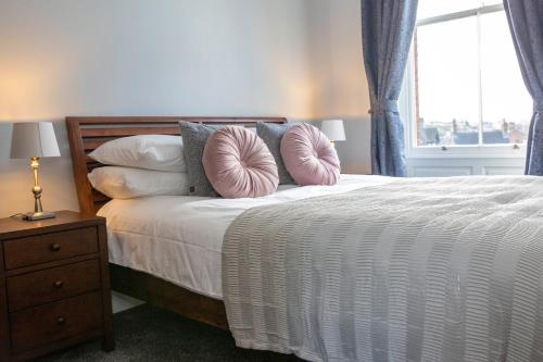 sypialnia z łóżkiem z poduszkami i oknem w obiekcie Dovedale w mieście Ashbourne