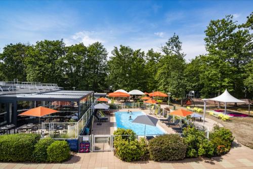 an outdoor swimming pool with umbrellas and a resort at Demeures de Campagne Chemins de Sologne à Orléans in Orléans