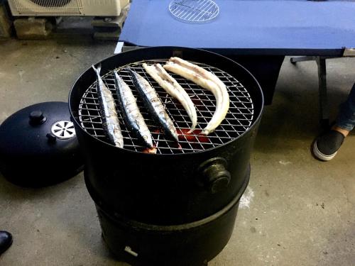 a grill with three sausages cooking on it at Oasis Wadaura in Minamiboso