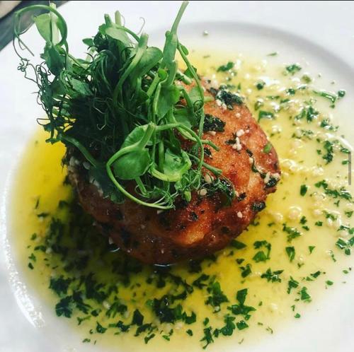 a plate of food with a piece of meat with sauce and greens at Michelangelos - Rooms, Restaurant & Bar in Gateshead