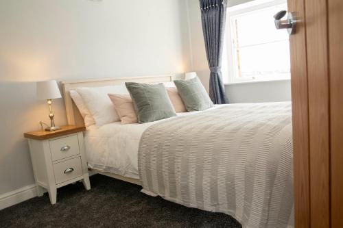 sypialnia z łóżkiem z poduszkami i oknem w obiekcie Manifold Dale w mieście Ashbourne