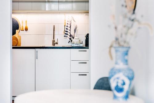 een keuken met witte kasten en een blauwe vaas bij West 7 in Zandvoort