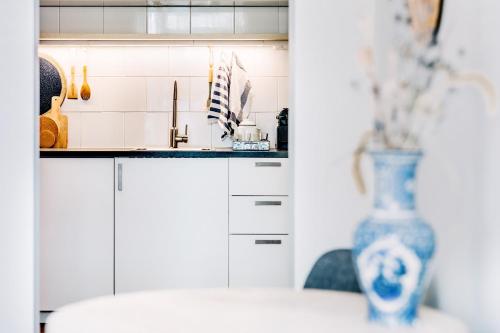 a kitchen with white cabinets and a blue vase at West 7 in Zandvoort