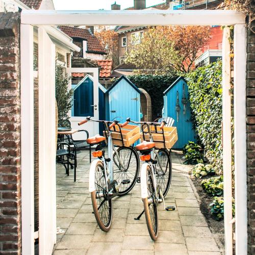 zwei Fahrräder unter einem Bogen mit blauen Türen in der Unterkunft West 7 in Zandvoort