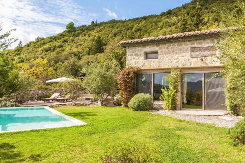 a stone house with a garden and a swimming pool at Mounty Island Villas-Nefeli in Lazaráta