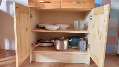 a wooden cupboard with dishes and plates in it at Tatralandia Apartmán in Liptovský Mikuláš