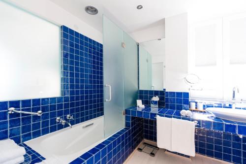 a blue tiled bathroom with a tub and a sink at The Albatroz Hotel in Cascais