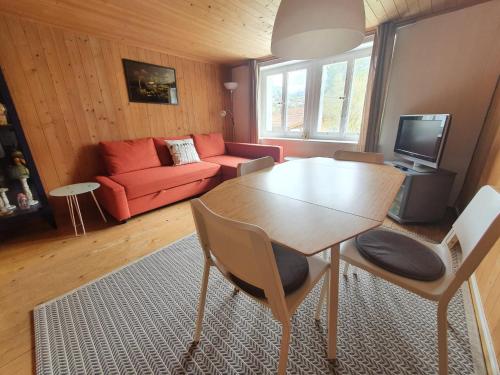 a living room with a table and a red couch at Apartment Lilalama in Grindelwald