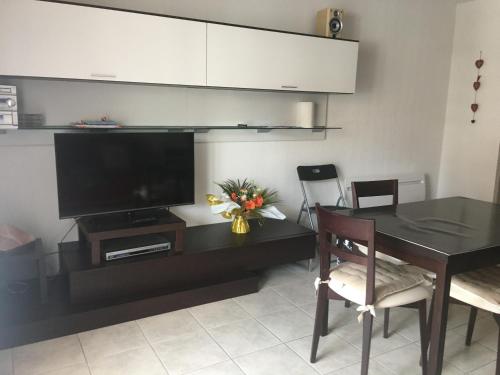 ein Wohnzimmer mit einem TV und einem Tisch mit Stühlen in der Unterkunft Studio 102 Les Sandia in Valberg