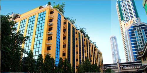 a tall yellow building with windows in a city at King Royal Garden Inn in Bangkok