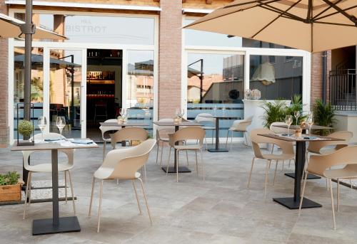un patio con mesas, sillas y sombrillas en LA COLLINA - camere & bistrot, en Erbusco