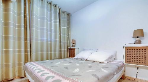 a small bedroom with a bed with a curtain at T 2 tout confort avec terrasse vue mer et montagne. in Banyuls-sur-Mer