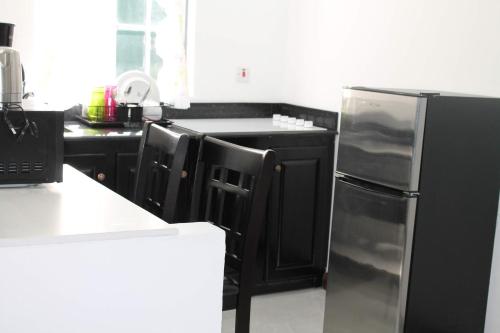 a kitchen with black cabinets and a stainless steel refrigerator at Sand and Blue Seas in Negril