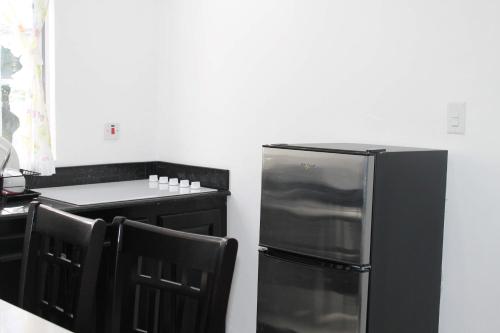 a kitchen with a black refrigerator and a counter at Sand and Blue Seas in Negril