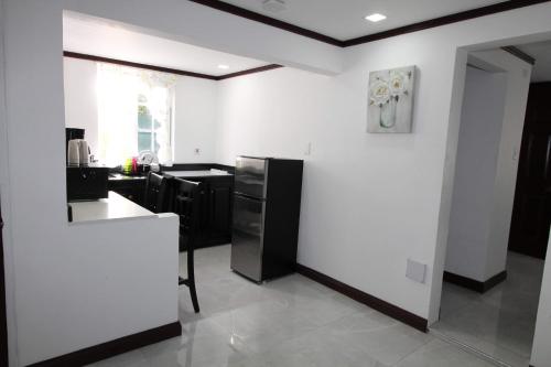a kitchen with white walls and black appliances at Sand and Blue Seas in Negril