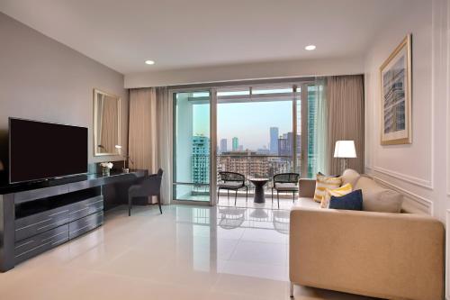 a living room with a couch and a tv at Dusit Suites Hotel Ratchadamri, Bangkok in Bangkok