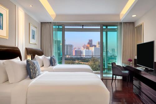 a hotel room with two beds and a television at Dusit Suites Hotel Ratchadamri, Bangkok in Bangkok