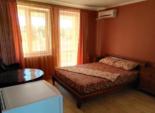 a bedroom with a bed and a table and windows at Mini-Dacha in Kurortne
