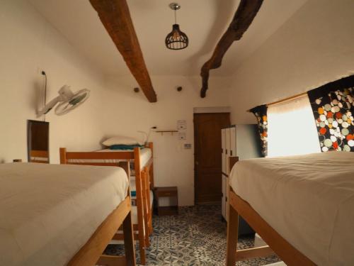a room with two beds and a refrigerator and a window at Rey Lagarto Hostel in San Pedro de Atacama