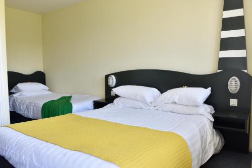 a room with two beds with white and yellow sheets at Hôtel Heod - Binic - Saint-Quay-Portrieux in Étables-sur-Mer