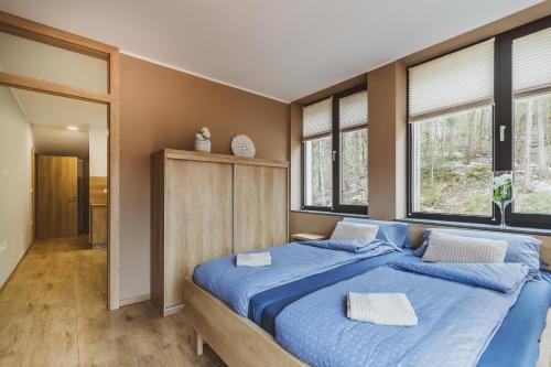 a bedroom with a large blue bed with windows at Center Vintgar in Slovenska Bistrica