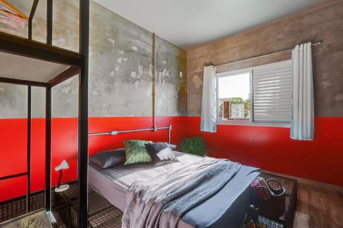 Un dormitorio con una cama con paredes rojas y una ventana en Campeche Apart, en Florianópolis