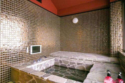 a bathroom with a bath tub in a tiled wall at Hana No Shizuku in Ureshino