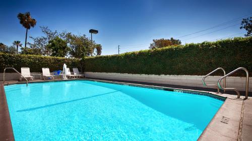 a large swimming pool with two chairs and a hedge at SureStay Hotel by Best Western Camarillo in Camarillo
