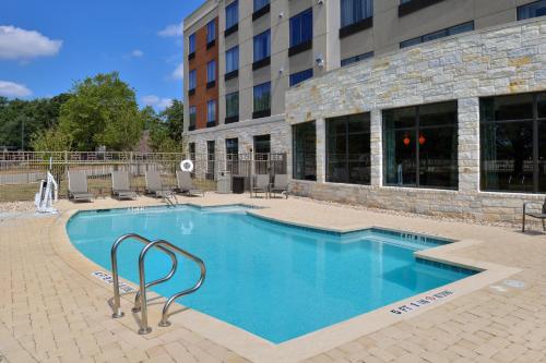 a large swimming pool in front of a building at Holiday Inn Express & Suites Austin South, an IHG Hotel in Austin