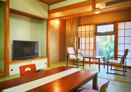 a living room with a television and a table and chairs at Nasu Hoshi no Akari in Nasu