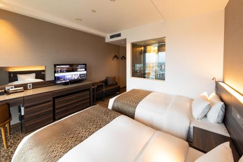 a hotel room with two beds and a flat screen tv at Piazza Hotel Nara in Nara