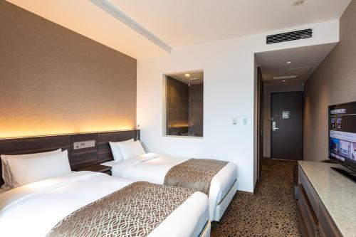 a hotel room with two beds and a flat screen tv at Piazza Hotel Nara in Nara