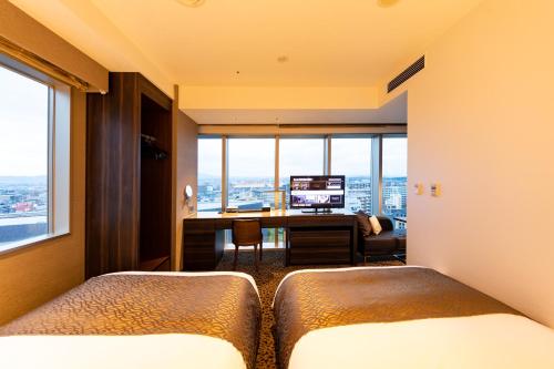a room with two beds and a desk with a computer at Piazza Hotel Nara in Nara