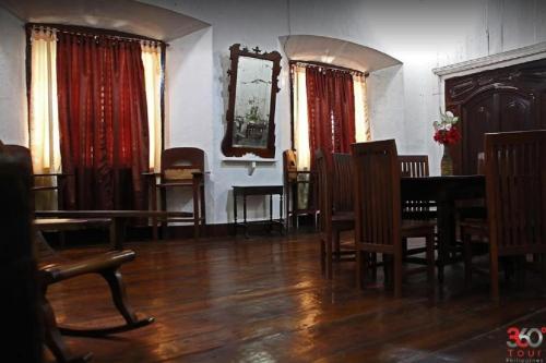 a dining room with a table and chairs and a mirror at Escolta's Homey Lodge in Vigan