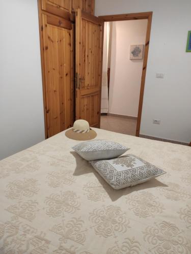 a bed with a hat and two pillows on it at Apartment Stella Maris in Cala Gonone